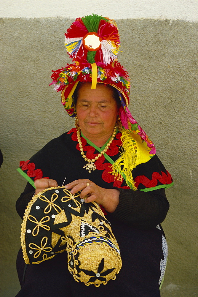 Portrait of a Spanish woman in traditional dress decorating a straw hat, in Extremadura, Spain, Europe