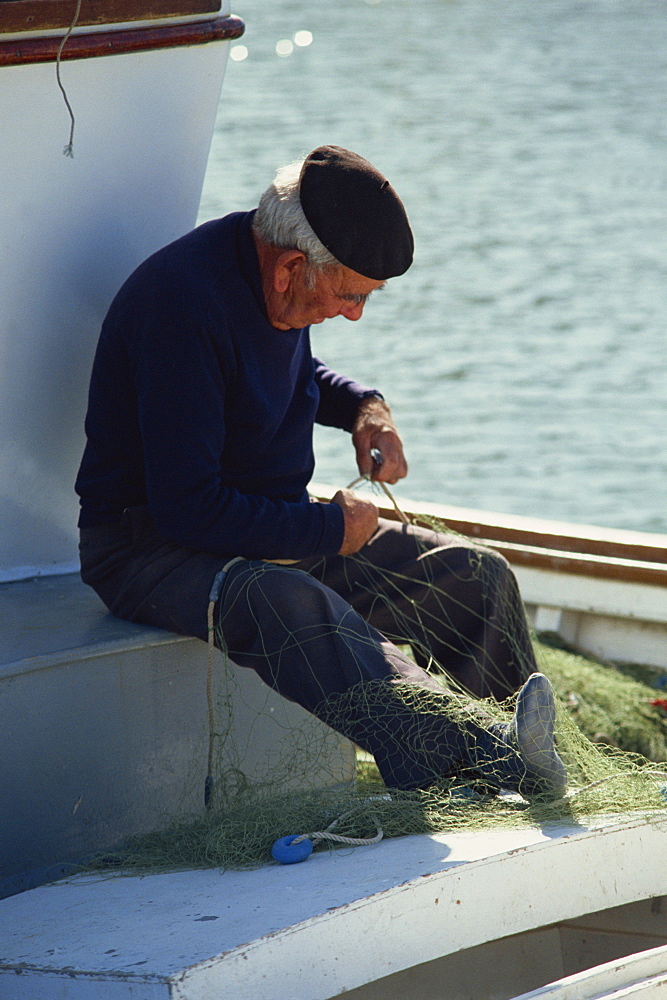 A Spanish fisherman in a beret mending his fishing nets on the Costa Brava, Catalunya (Catalonia) (Cataluna), Spain, Europe