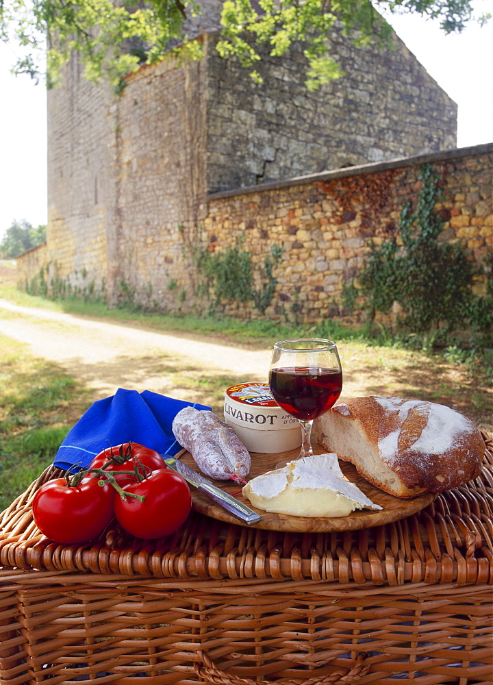 Picnic lunch of bread, cheese, tomatoes and red wine on a hamper in the Dordogne, France 