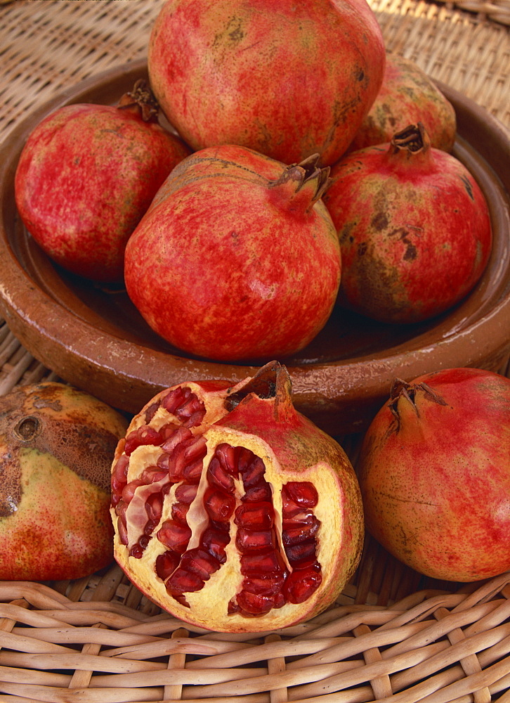 Still life of a bowl of red pomegranates, with one fruit cut in half to show seeds, in Andalucia (Andalusia), Spain, Europe