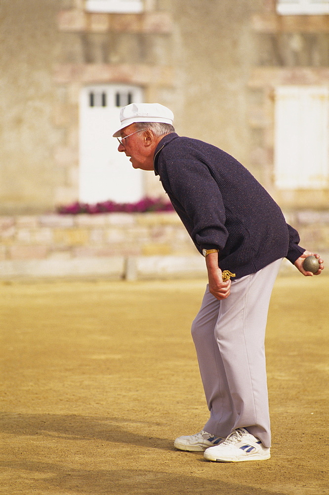 Portrait of an elderly French man in casual clothing, wearing trainers, playing petanques in Brittany, France, Europe