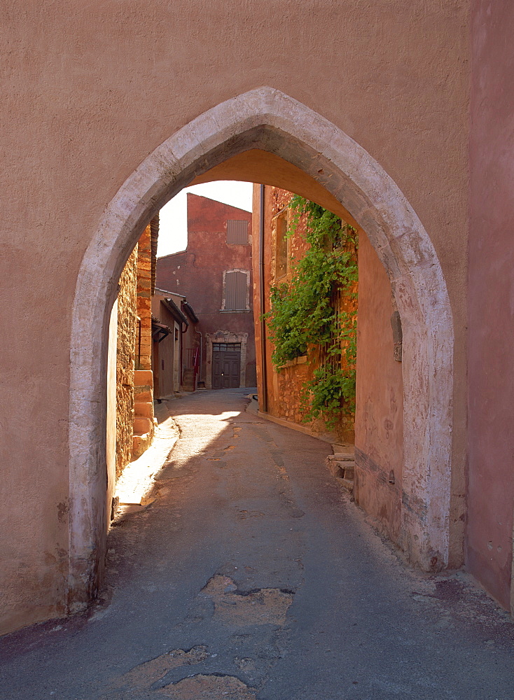 Pink arch over a narrow empty street in the village of Roussillon, Vaucluse, Provence, France, Europe