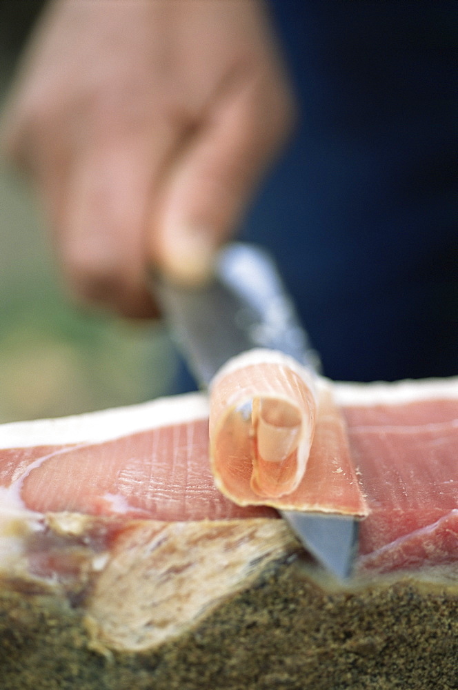 Man finely slicing ham