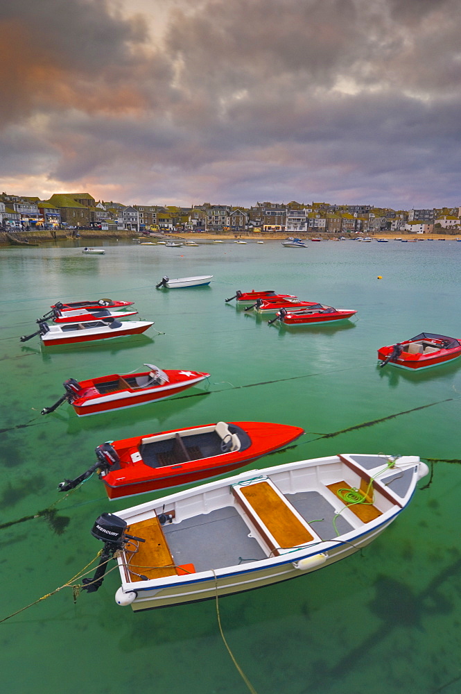 Strange cloud formation in a stormy sky at sunset, with small red speedboats for hire with an incoming tide in the harbour at St. Ives, Cornwall, England, United Kingdom, Europe