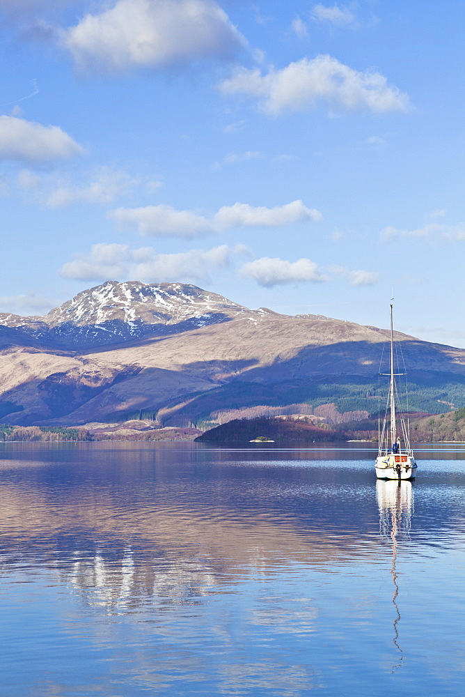 Picturesque tranquil Loch Lomond with sailing boat, snow covered Beinn Uird behind, from Luss Jetty, Luss, Argyll and Bute, Scotland, United Kingdom, Europe