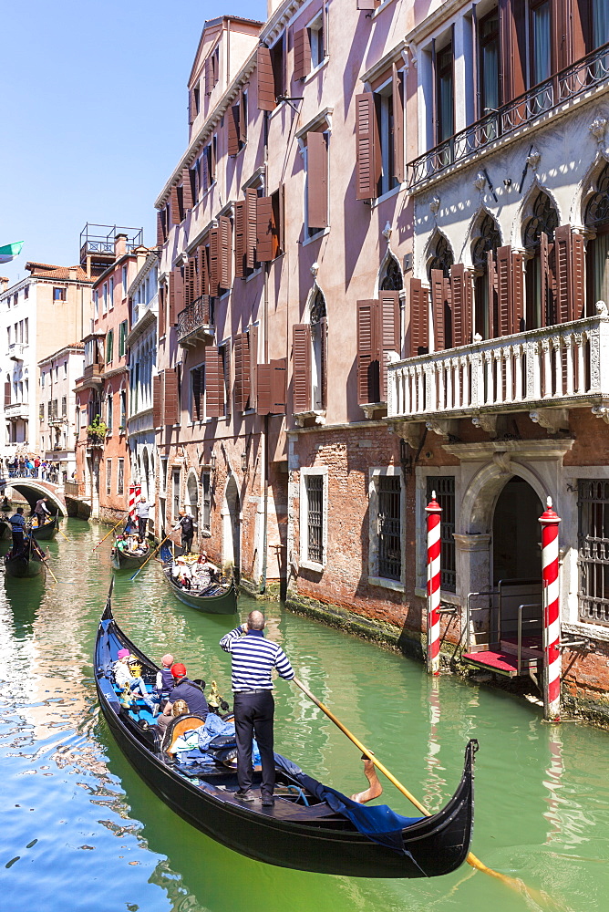 Gondolier, rowing a gondola, with tourists, along canal, in front of a palazzo, Venice, UNESCO World Heritage Site, Veneto, Italy, Europe