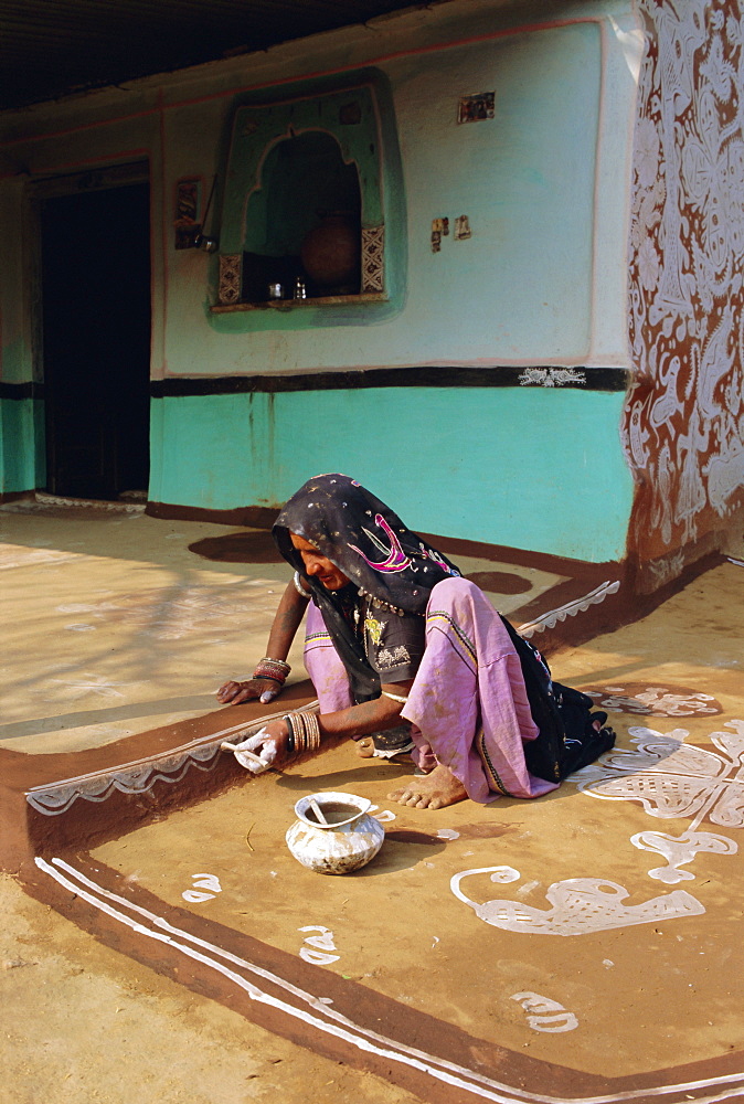 Woman painting the wall of a village house, Tonk region, Rajasthan, India