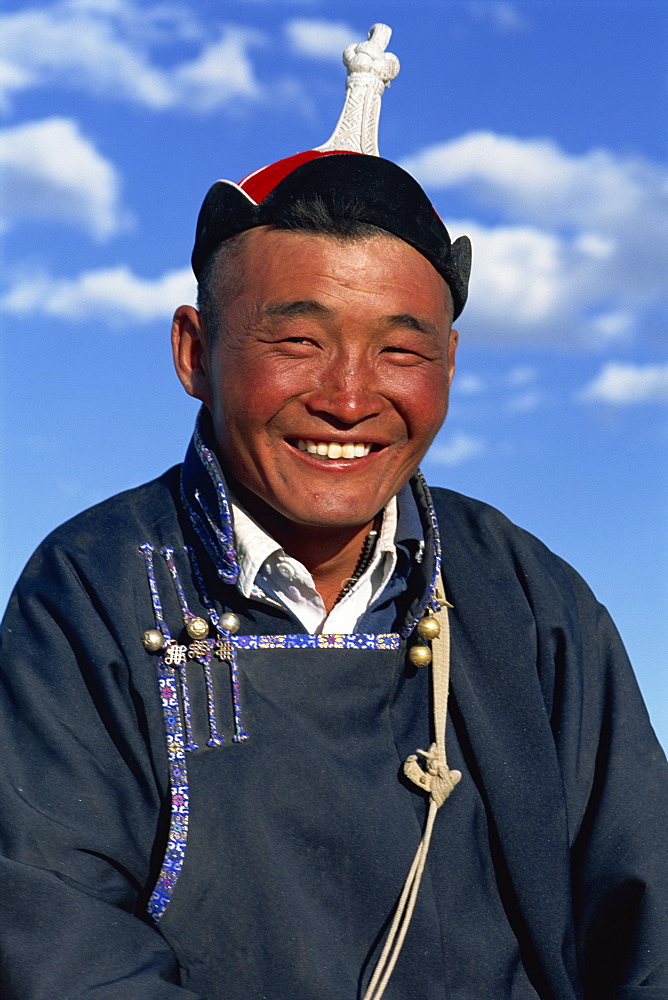 Head and shoulders portrait of a smiling nomad man in traditional clothing, looking at the camera, at Naadam Festival, Altai, Gov-altai, Mongolia, Central Asia, Asia