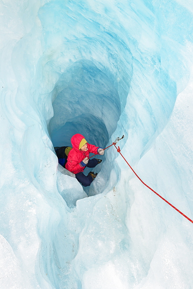 Rock climber moving up ice cave, Fox Glacier, South Island, New Zealand, Pacific