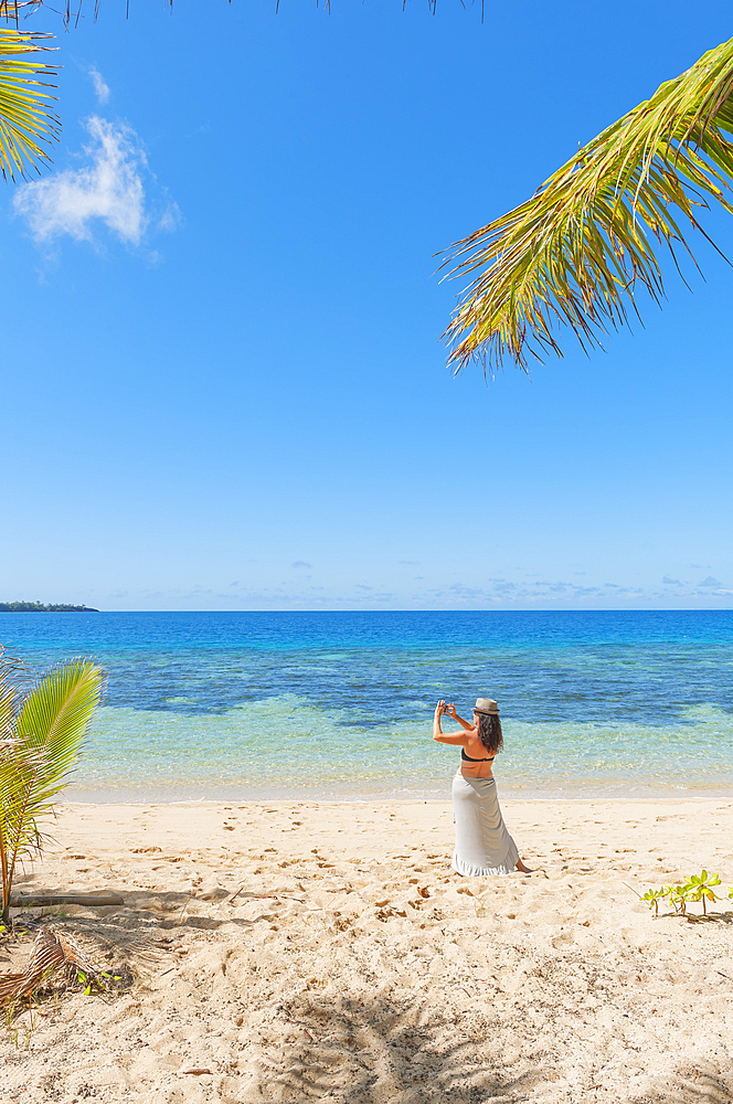 Woman taking photographs on a tropical beach, Drawaqa Island, Yasawa islands, Fiji, South Pacific Islands, Pacific