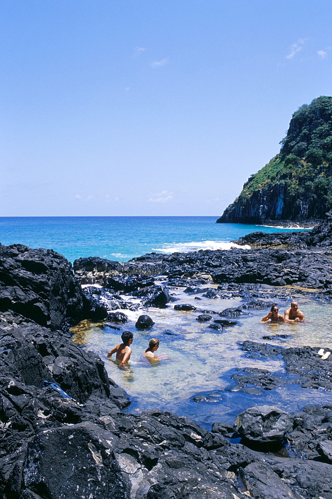 People swimming at Baia dos Porcos inside natural swimming pools, Parque Nacional de Fernando de Norohna, Fernando de Noronha, Pernambuco, Brazil, South America