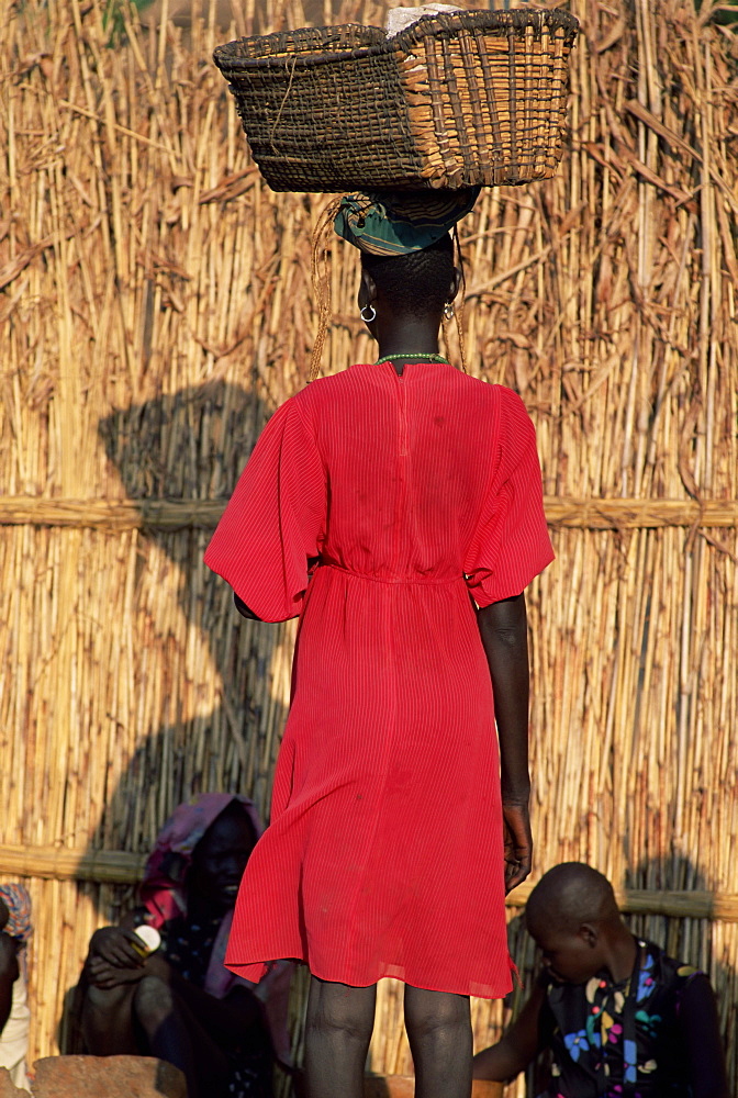 Back view of a Nuer woman carrying a wicker cradle or crib on her head, Itang region, Ilubador state, Ethiopia, Africa