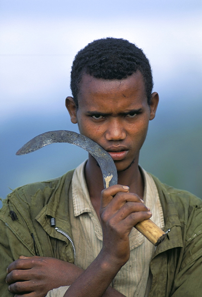 Portrait of a young man holding a sickle, Oromo country, Bako region, Shoa state, Ethiopia, Africa