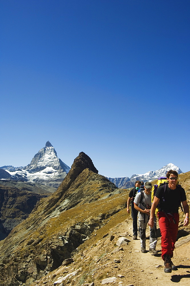 Hikers walking on trail with the Matterhorn, 4477m, beyond, Zermatt Alpine Resort, Valais, Switzerland, Europe 