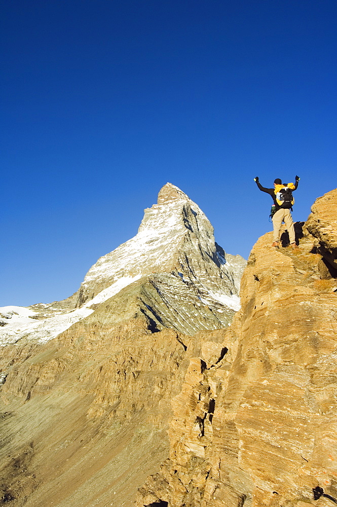 Hiker on trail celebrating at the sight of the Matterhorn, 4477m, Zermatt Alpine Resort, Valais, Switzerland, Europe