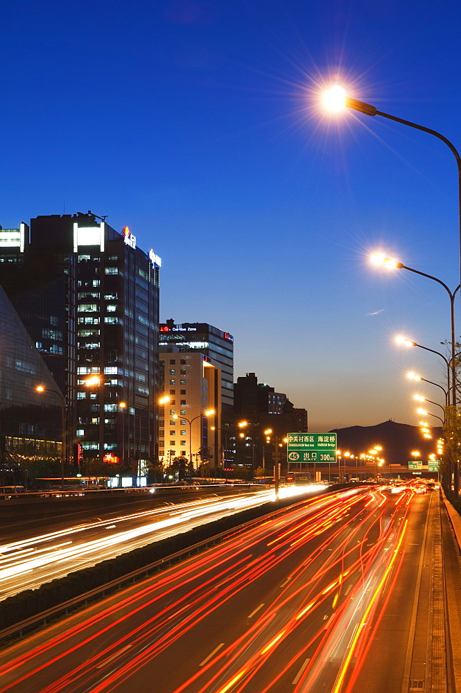 Car light trails and modern architecture on a city ring road, Beijing, China, Asia