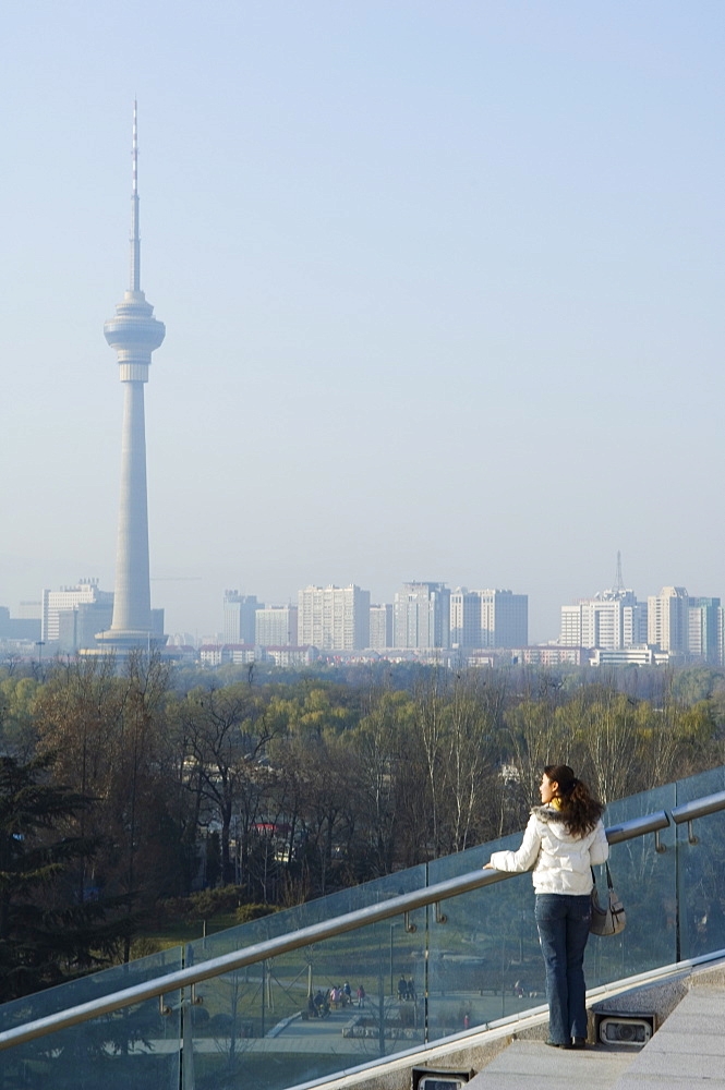 A Chinese girl in front of The CCTV Tower (China Central Television), Beijing, China, Asia