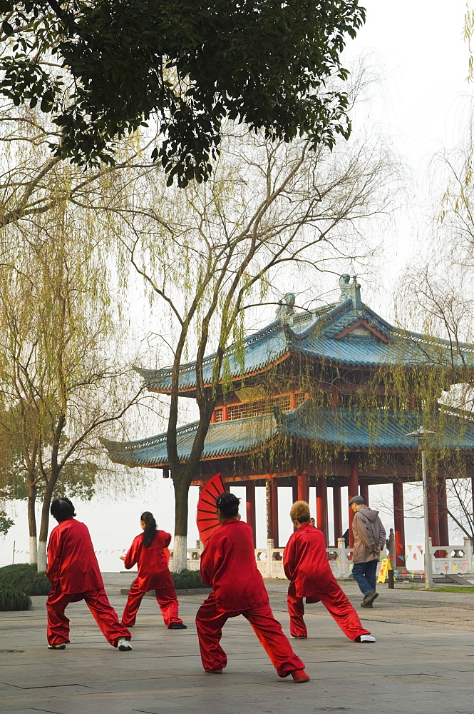 Women practising tai chi in front of a pavilion on West Lake, Hangzhou, Zhejiang Province, China, Asia