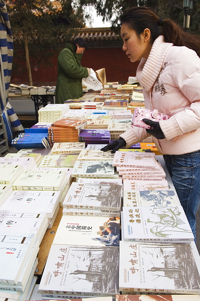 A Chinese girl looking for books at Ditan Park book fair, Beijing, China, Asia