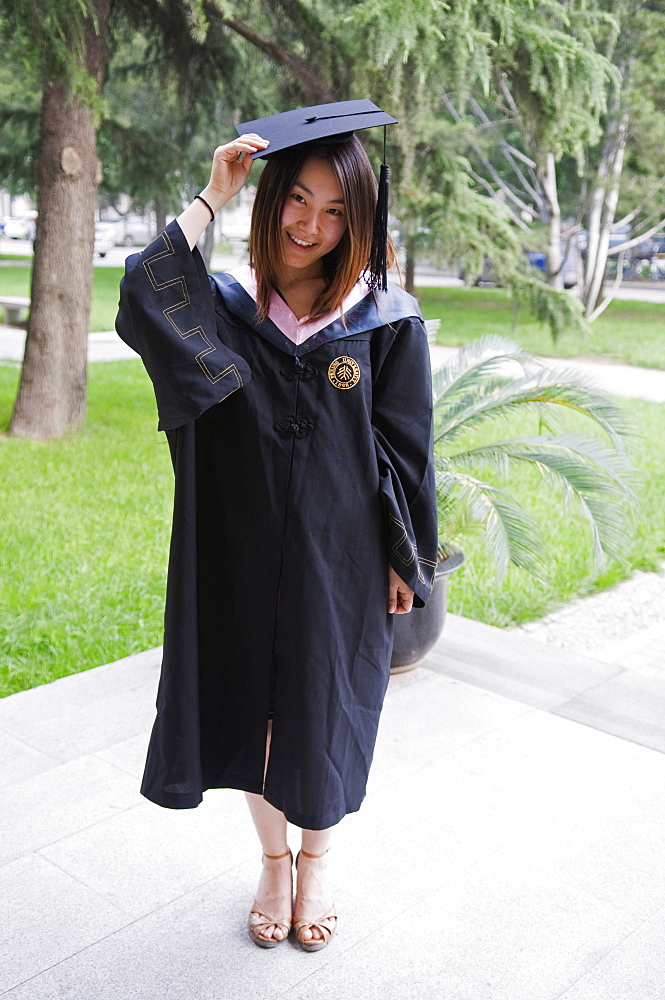 A female student on Graduation Day in front of a Chinese gate at Peking University, Beijing, China, Asia