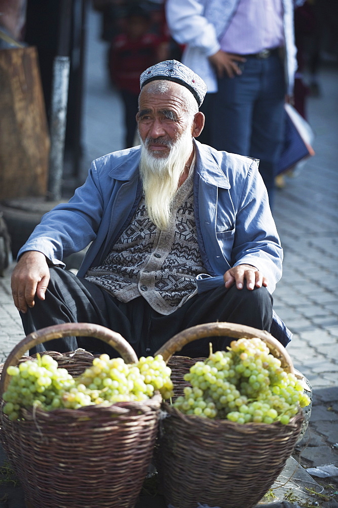 Bearded man selling grapes at the Sunday market, Kashgar (Kashi), Xinjiang Province, China, Asia