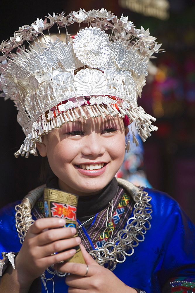 Girl in traditional clothing welcoming visitors with a horn of rice wine at a Miao New Year festival in Xijiang, Guizhou Province, China, Asia