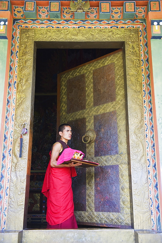 Young monk at a temple doorway, Khamsum Yuelley Namgyal Chorten built in 1999, Punakha, Bhutan, Asia