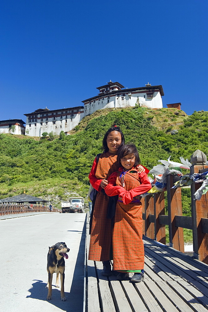 Two girls and dog on a bridge below Wangdue Phodrang Dzong, founded by the Zhabdrung in 1638, Bhutan, Asia