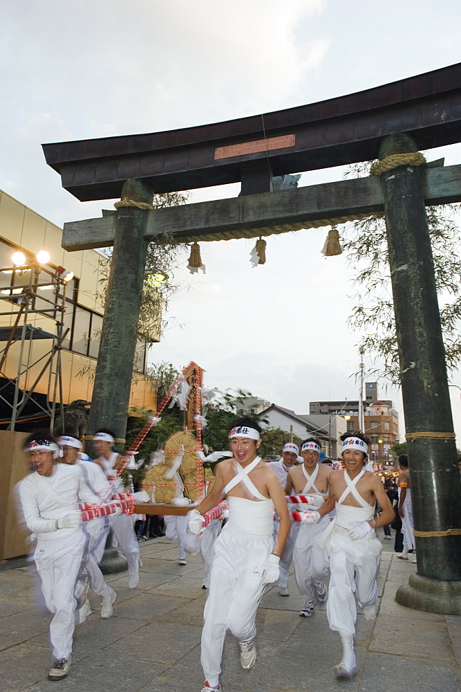 Rice bales being carried through a torii gate at Hadaka Matsuri (Naked Festival), Hofu city, Yamaguchi Prefecture, Japan, Asia