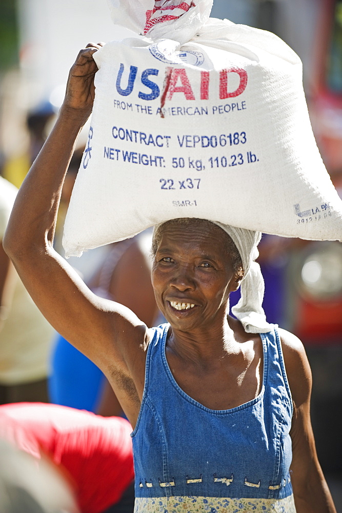 A woman carrying rice, USAid food distribution after the January 2010 earthquake, Port au Prince, Haiti, West Indies, Caribbean, Central America