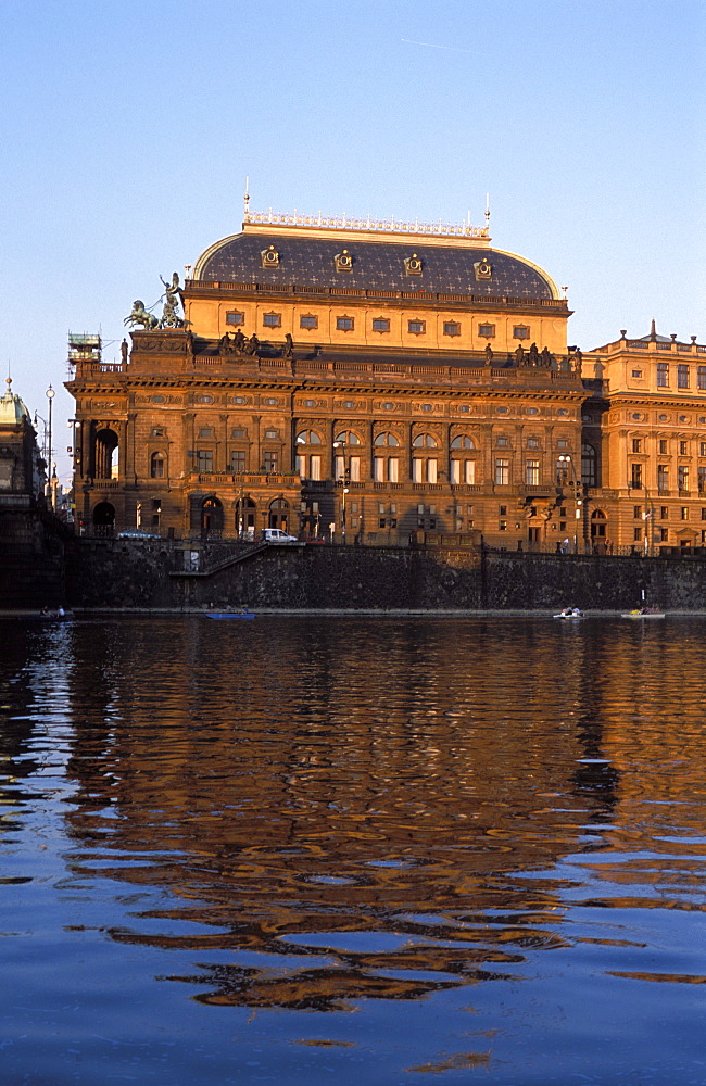 Exterior of the National Theatre (19th century) bathed in reddish glow of setting sun, popular for ballet and opera, from across the Vltava River, Nove Mesto, Prague, Czech Republic, Europe