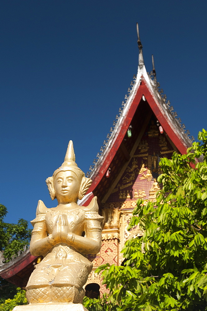 Statue of a kneeling figure praying in front of Temple of Wat Sop Sickharam, Luang Prabang, Laos, Indochina, Southeast Asia, Asia