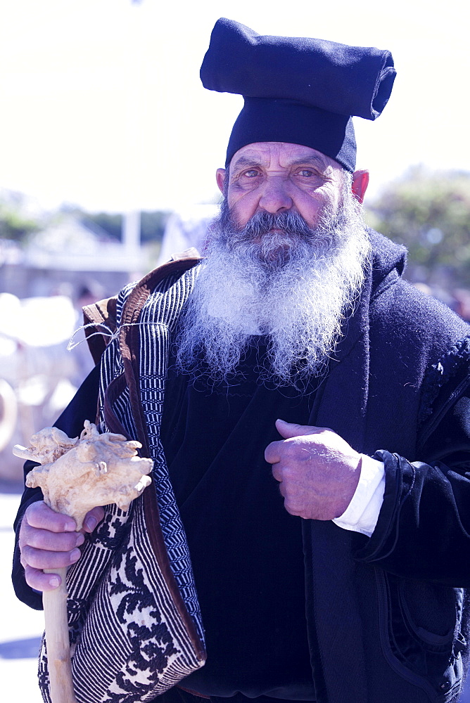 Man wearing the traditional Berritta Sardinian hat and carring the traditional double Sardinian sac, St. Antioco celebrations, Sant'Antioco,Sardinia, Italy, Europe