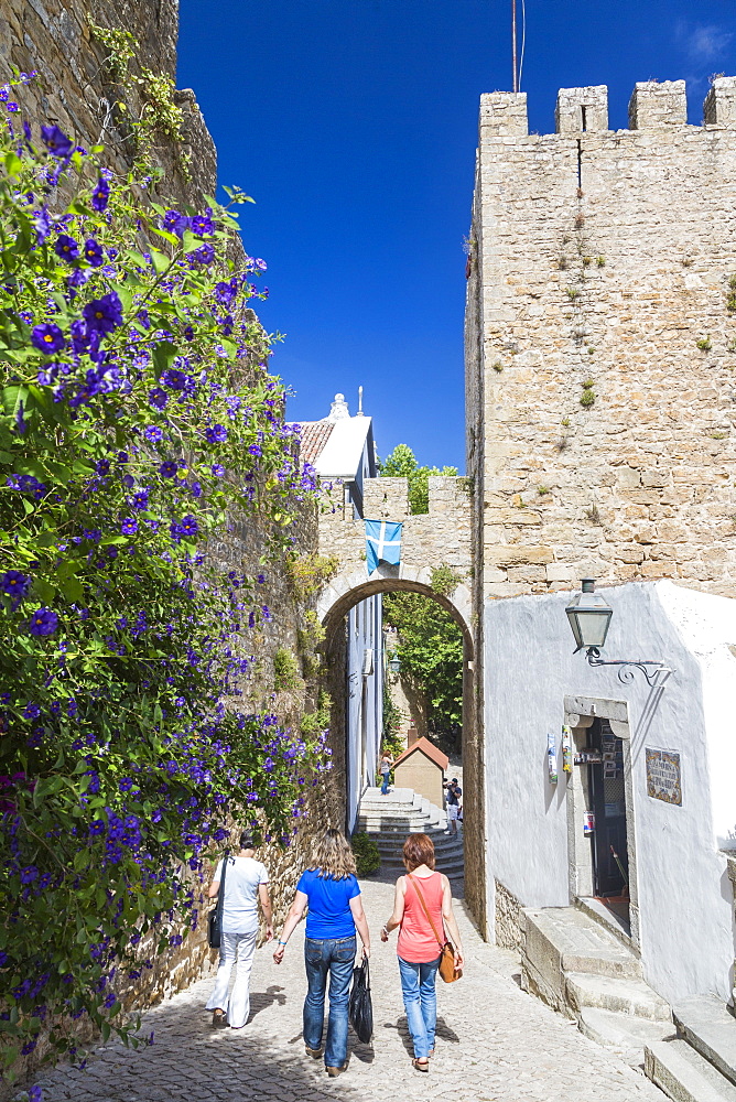 Tourists walk in the alleys close to the old castle in the fortified town of Obidos, Oeste, District of Leiria, Portugal, Europe