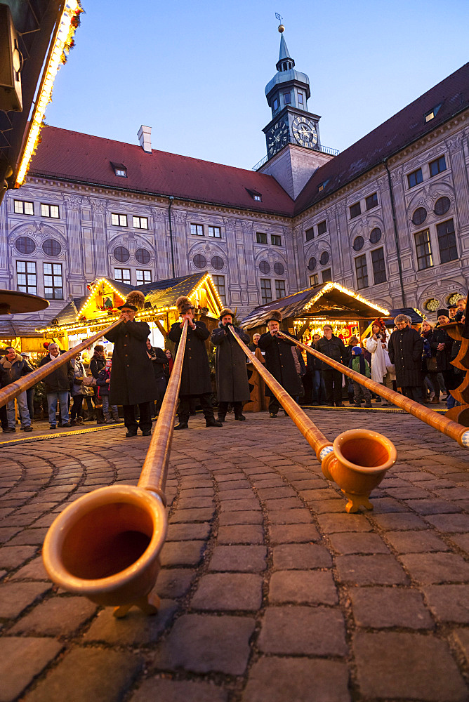 Christmas market in Munich. The alpine  Christmas Village in the Kaiserhof of the Residenz, the palace of the bavarian kings. Concert with Alpenhorn (Alphorn). Europe, Germany, Bavaria, Munich