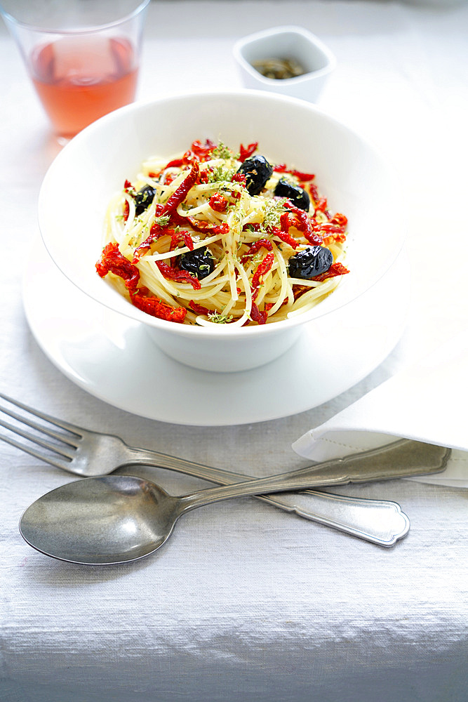 Durum wheat spaghetti pasta seasoned with dried tomatoes, black olives, Pantelleria capers, oregano and extra virgin olive oil, Italy, Europe