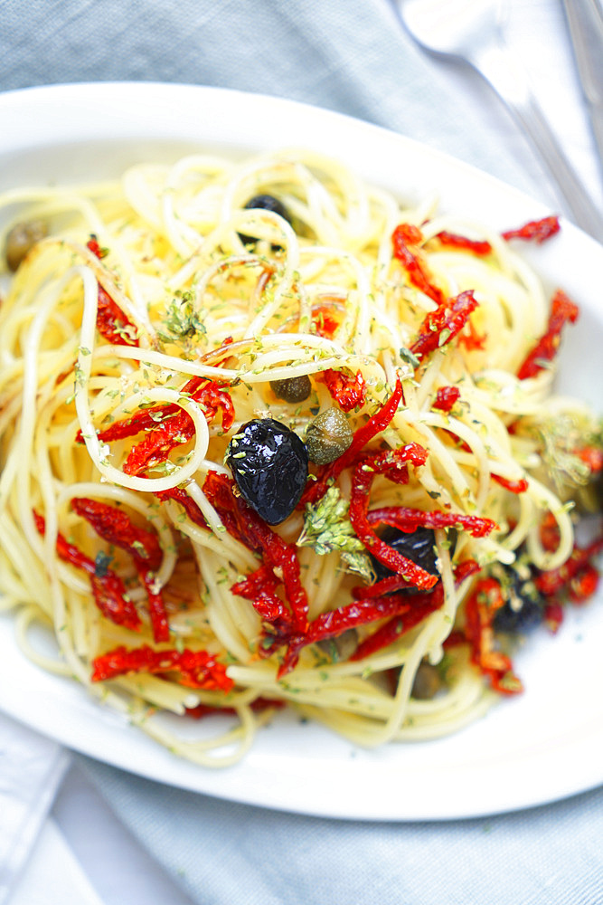 Durum wheat spaghetti pasta seasoned with dried tomatoes, black olives, Pantelleria capers, oregano and extra virgin olive oil, Italy, Europe