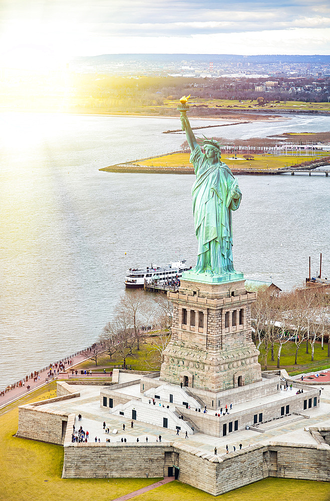 Statue of Liberty on Liberty Island and Ferry Boat with tourists, New York City.