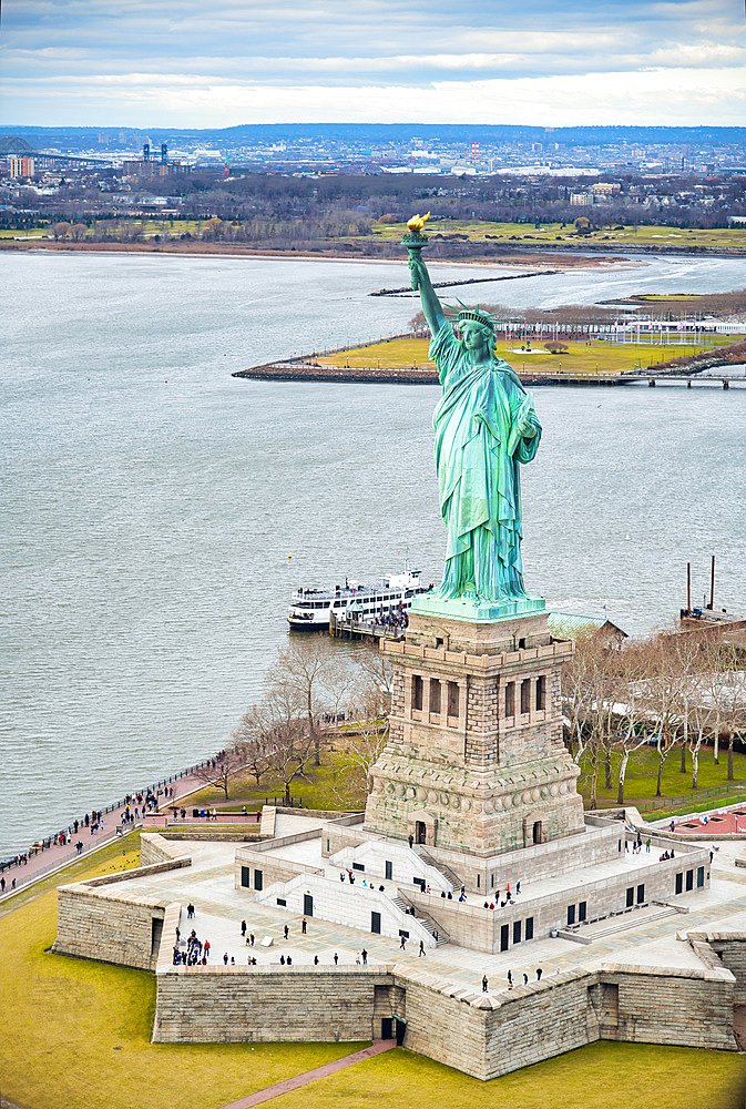 Statue of Liberty on Liberty Island and Ferry Boat with tourists, New York City.