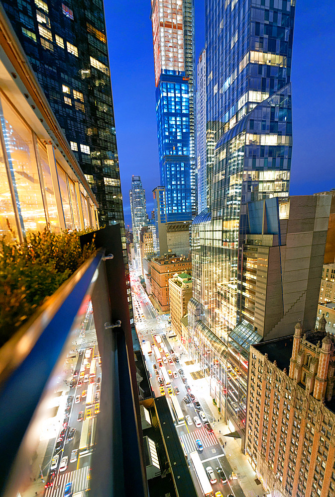 Amazing skyscrapers in Midtown Manhattan, aerial view from rooftop with traffic reflections on the buildings at night.