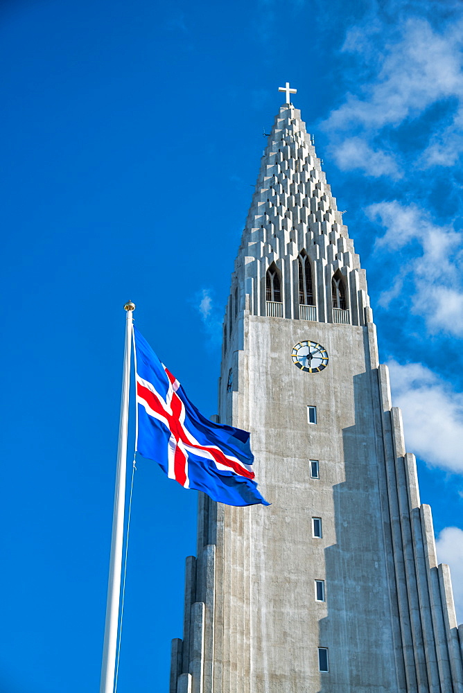 Hallgrimskirkja. Cathedral of Reykjavik with waving Iceland flag on a beautiful day.