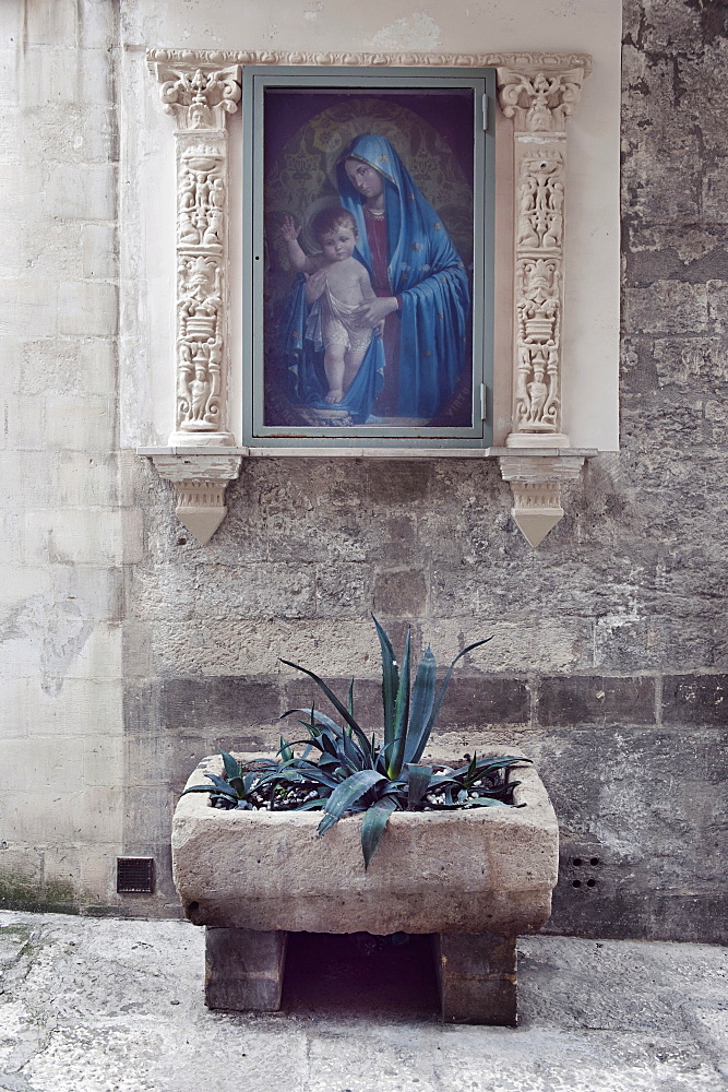 A votive aedicule depicting the Madonna in one of the main streets of the Sassi in Matera. The Sassi di Matera are ancient cave dwellings in the Italian city of Matera, Basilicata. Situated in the old town, they are composed of the Sasso Caveoso and the later Sasso Barisano. Matera, Basilicata, Italy, Europe