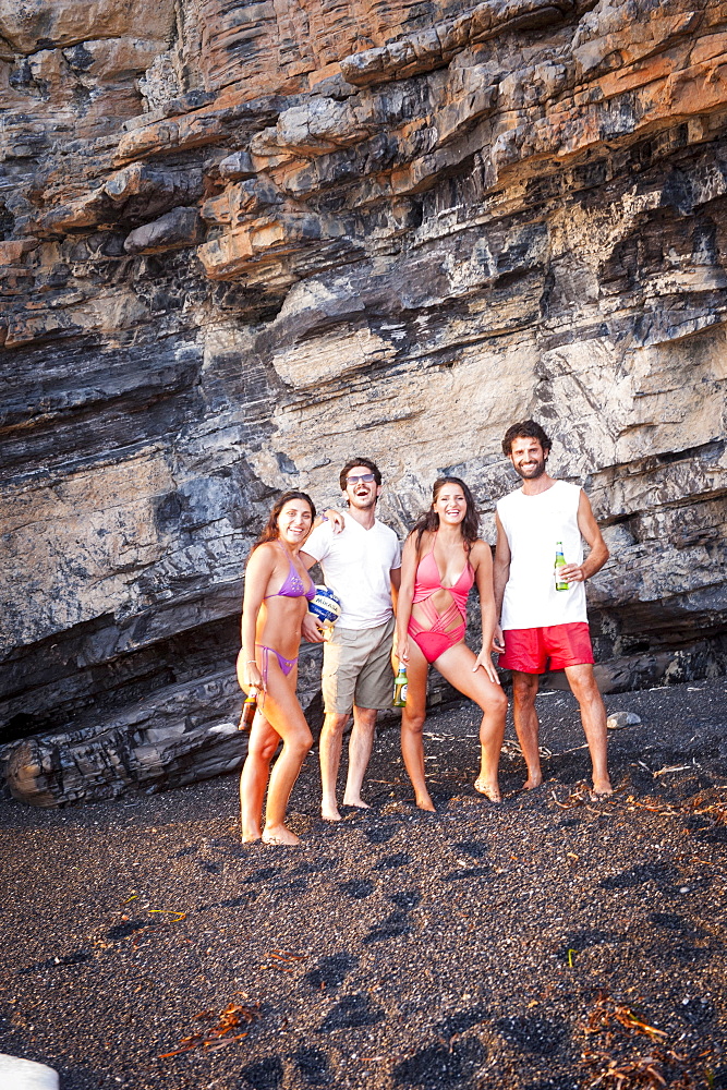 Group of smiling boys and girls on the Black Beach of Maratea at sunset, Basilicata, Italy, Europe