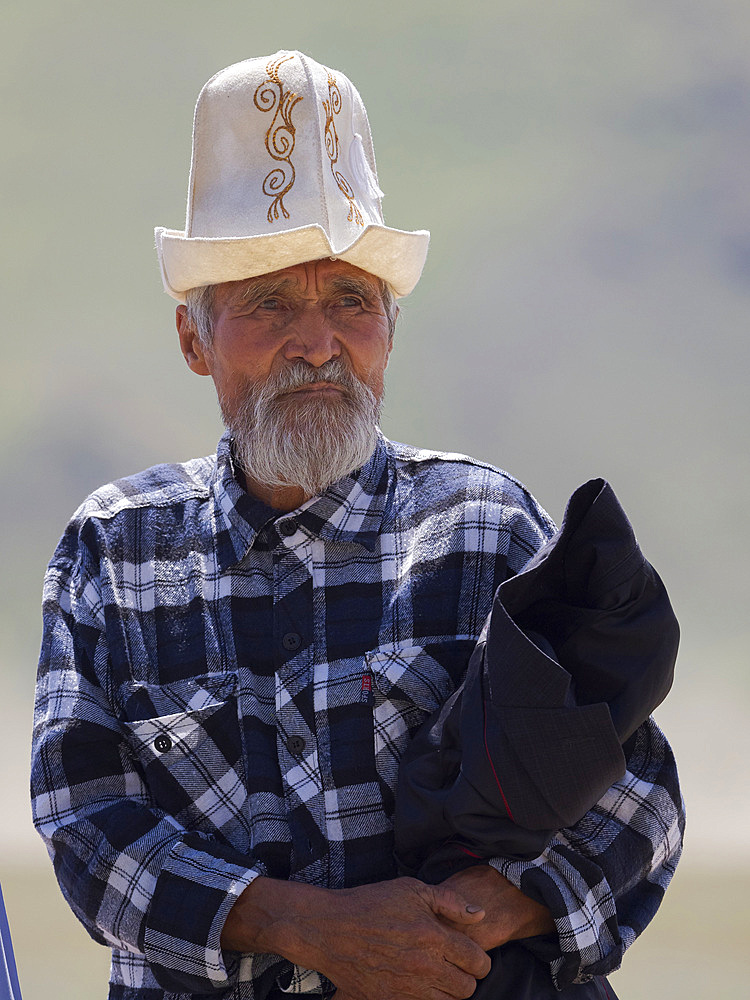 Man with traditional white felt hat, Kalpak. Folk and Sport festival on the Suusamyr plain commemorating Mr Koshomkul, a sportsman and folk hero of the last century. Asia, central asia, Kyrgyzstan