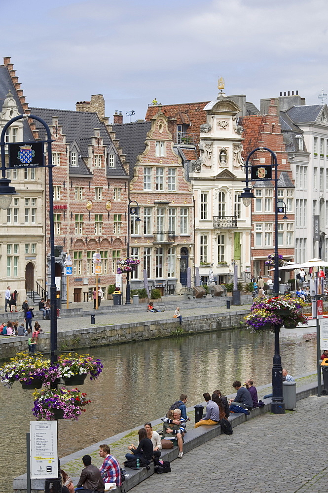 Students relaxing along the banks of the Graslei, Baroque style Flemish gables in the background, Ghent, Belgium, Europe