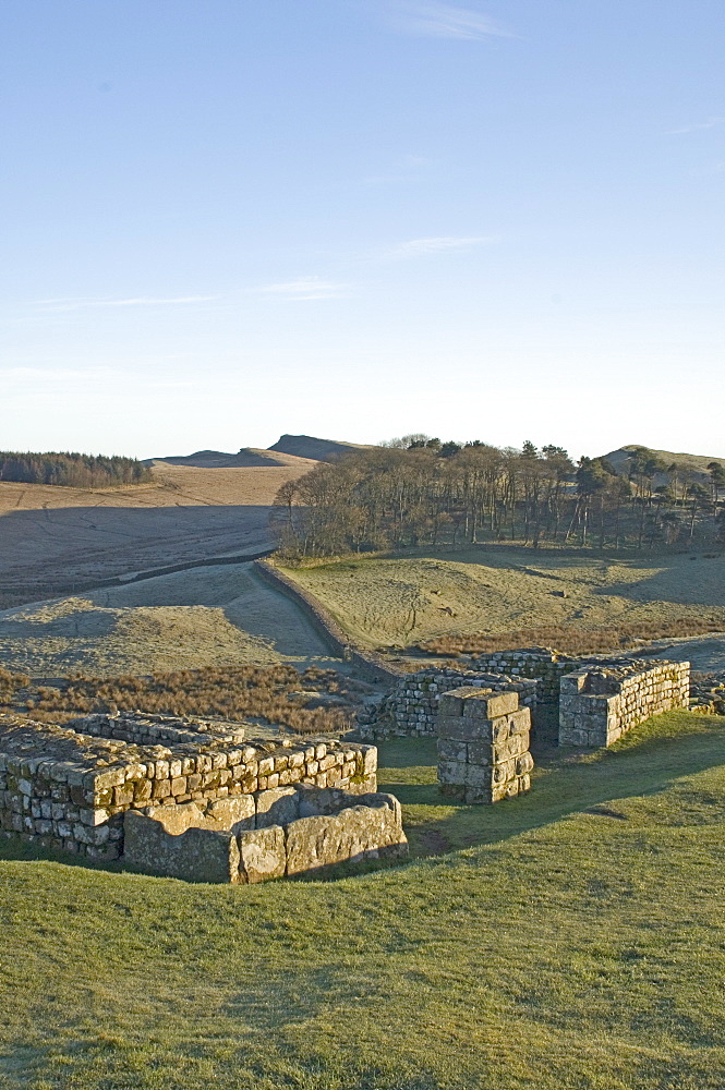 North gateway to Housesteads Roman Fort, stone water storage tank in foreground, looking east to Sewingshields Crag, Hadrians Wall, UNESCO World Heritage Site, Northumbria, England, United Kingdom, Europe