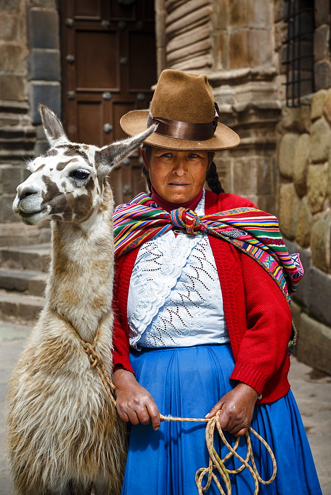 Portrait of a Quechua woman with llama along an Inca wall in San Blas neighborhood, Cuzco, Peru, South America