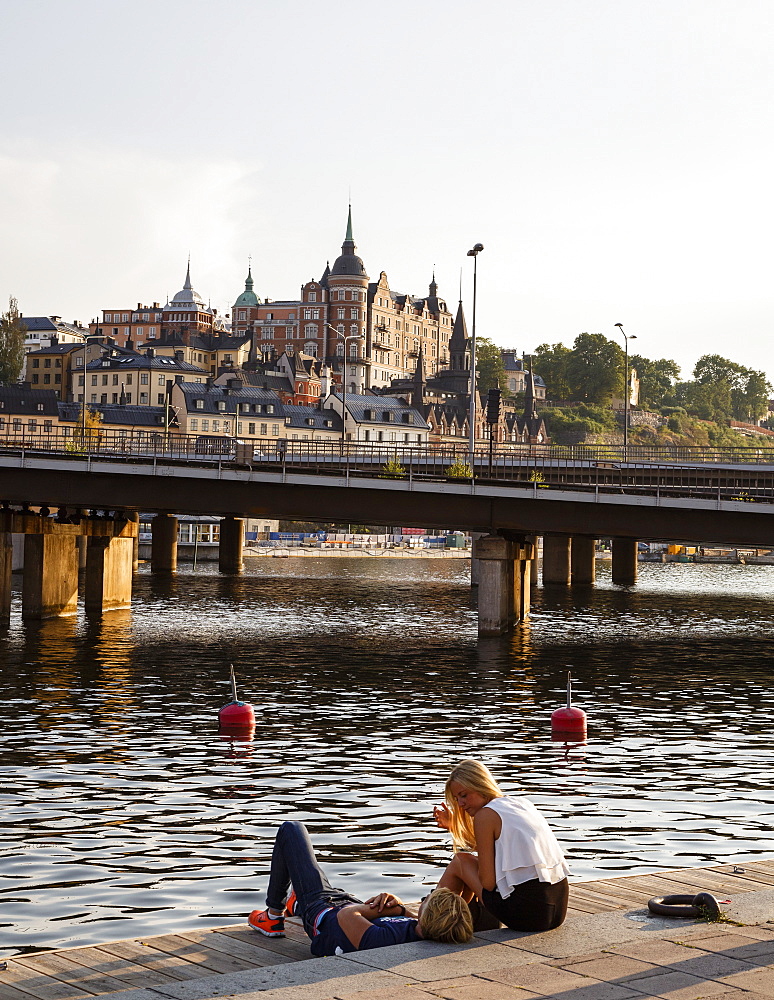 Couple sitting by the water overlooking Sodermalm and Riddarholmen, Stockholm, Sweden, Scandinavia, Europe