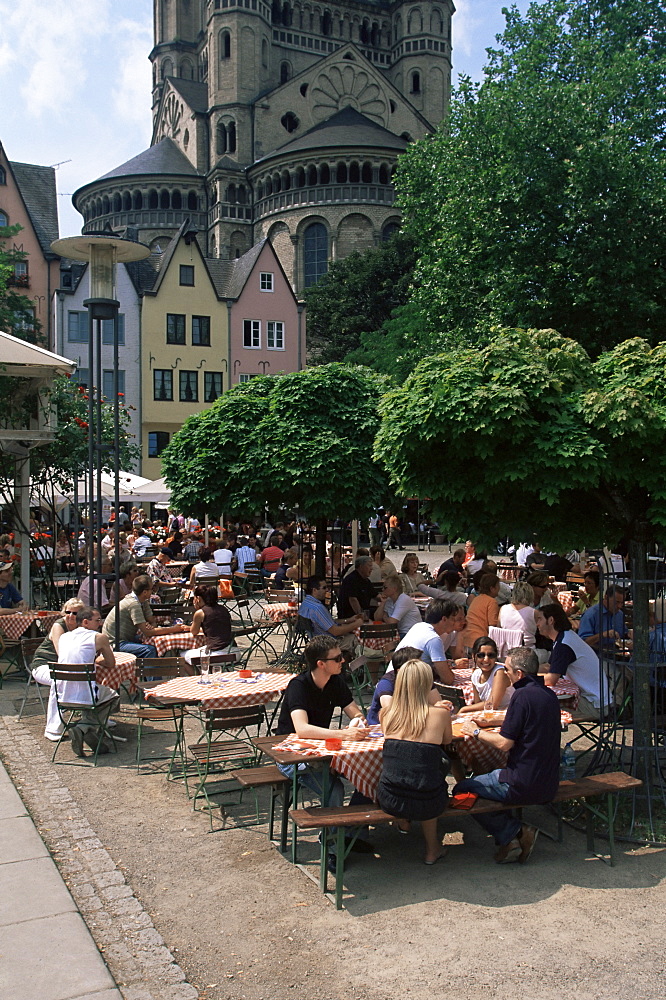 People sitting at an outdoors restaurant near St. Martin church which rises above the Fish Market in the old town, Cologne, North Rhine Westphalia, Germany, Europe