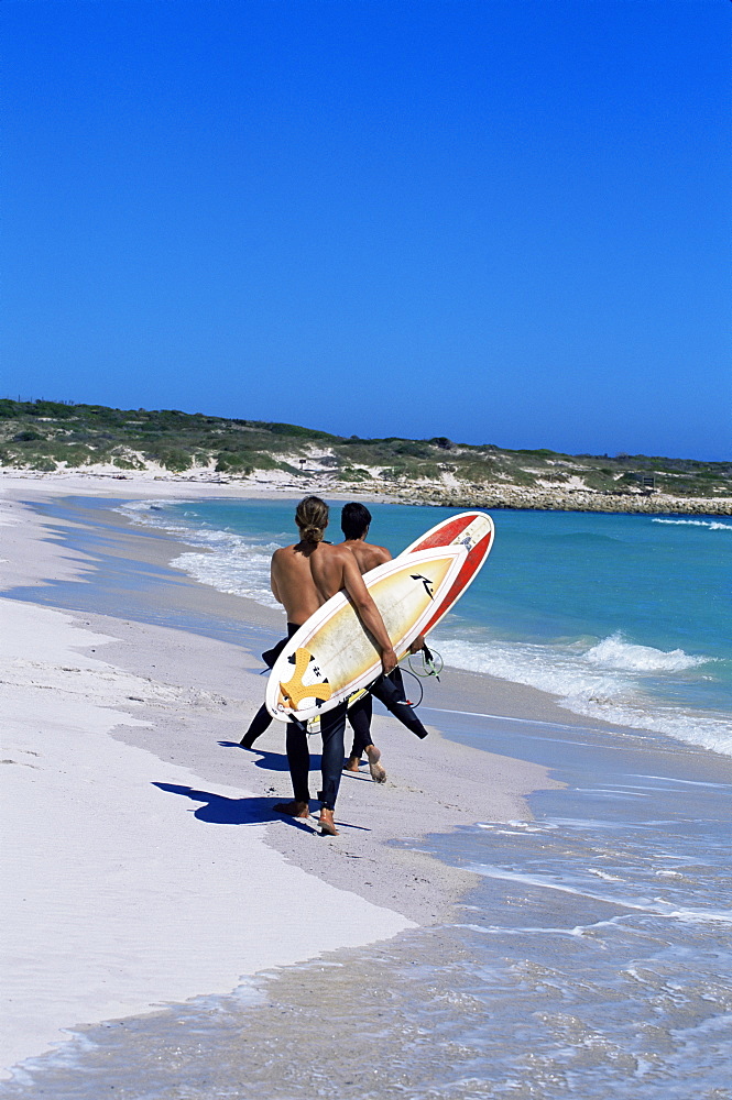 Two surfers walking with their boards on Kommetjie beach, Cape Town, South Africa, Africa